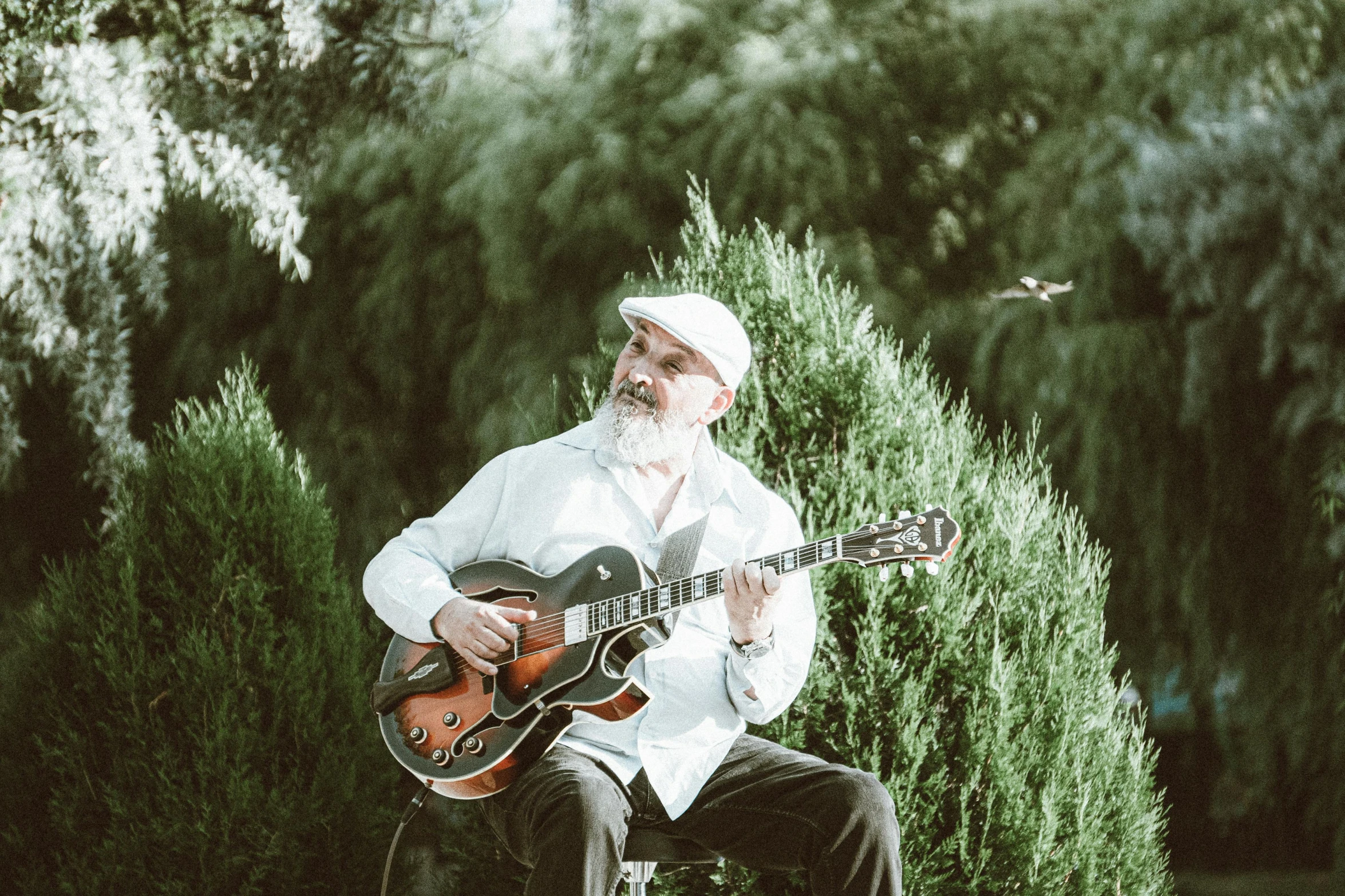 an older man with a white suit and hat playing guitar