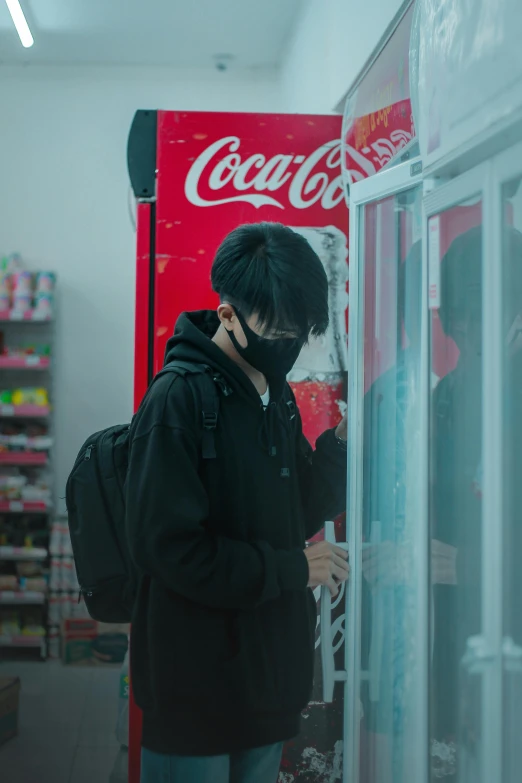 a man standing in front of a soda machine talking on the phone