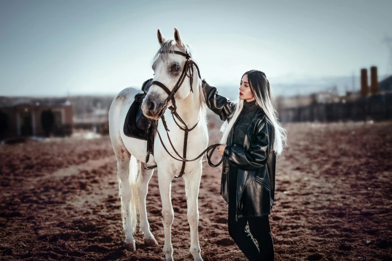 a woman standing next to a white horse in a field