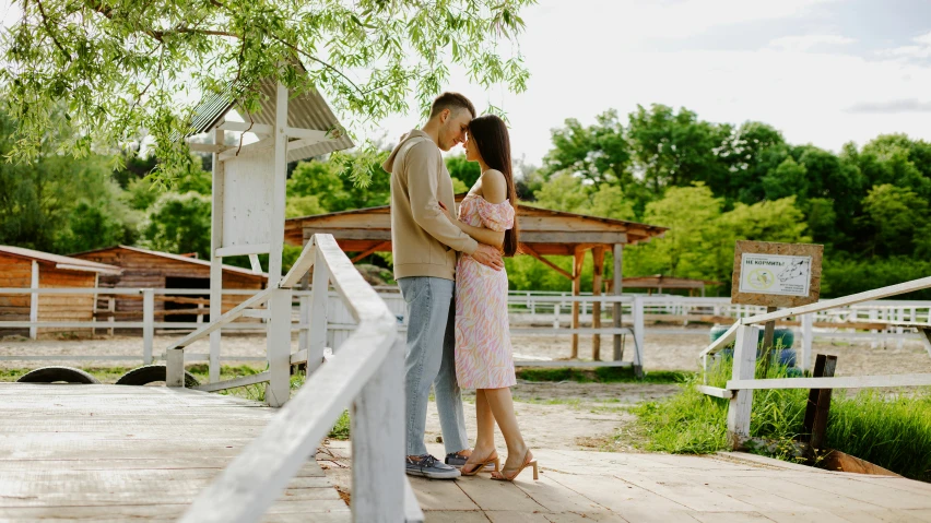 a couple standing together next to a fence near a park