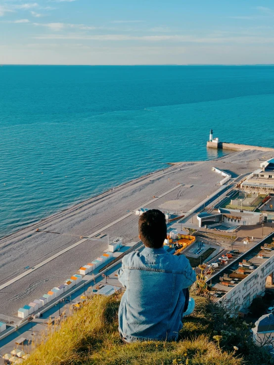 person sitting on a cliff watching an ocean