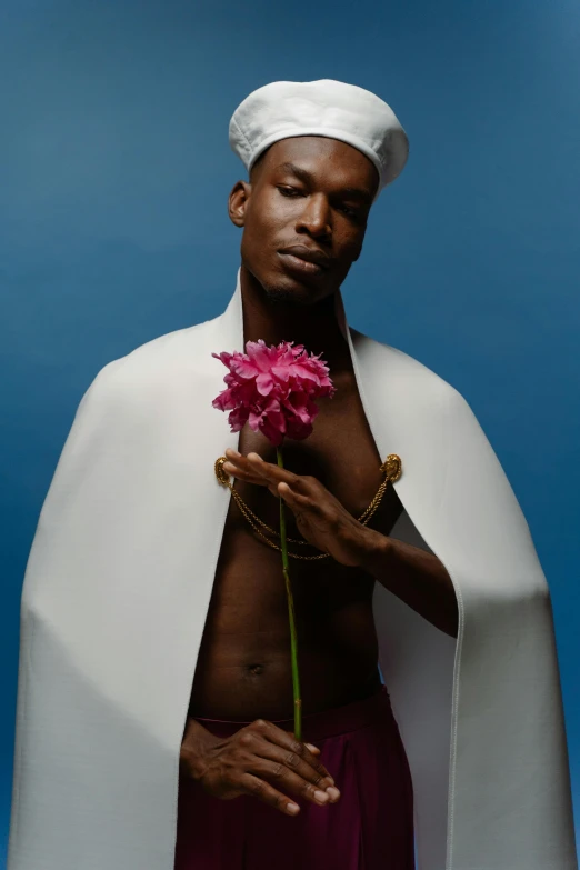 an african man holding a flower wearing white