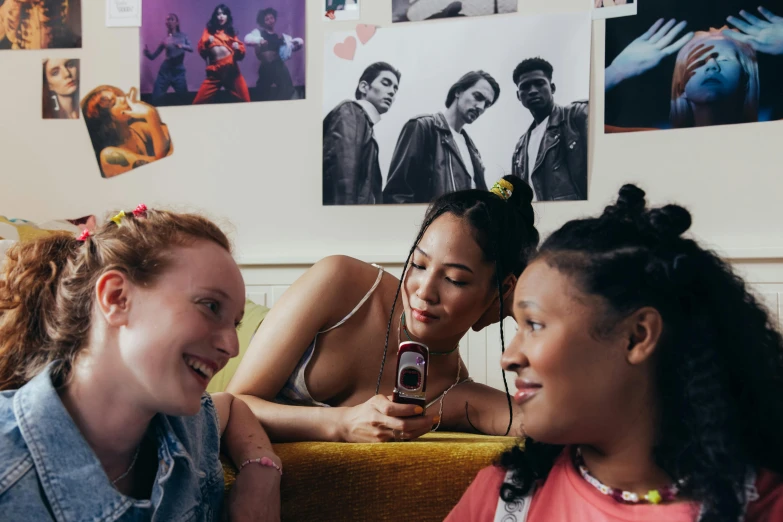 a group of girls sit on a couch talking and looking at a phone