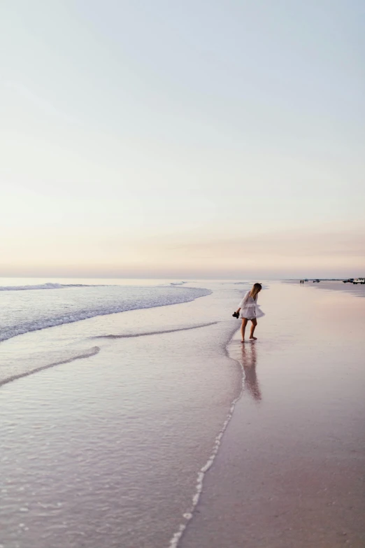 a girl walking along the edge of the ocean