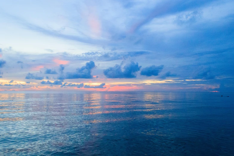 the clouds and water are very blue and the sun is setting