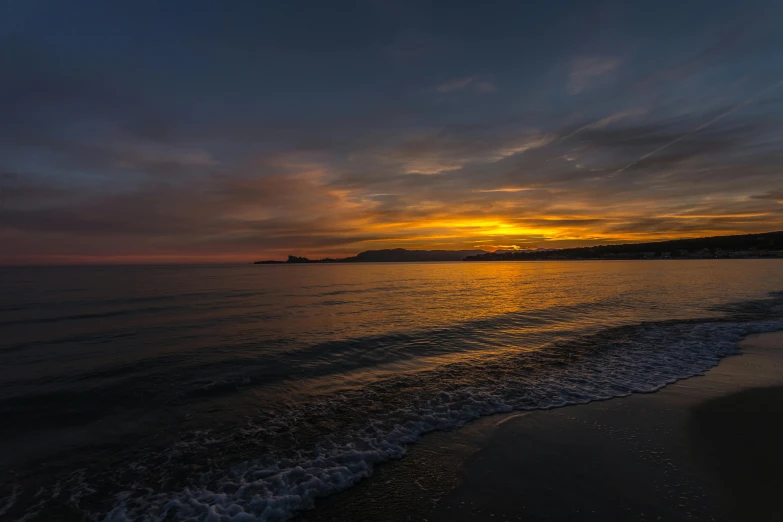 the ocean is calm and the sun rises behind a small island