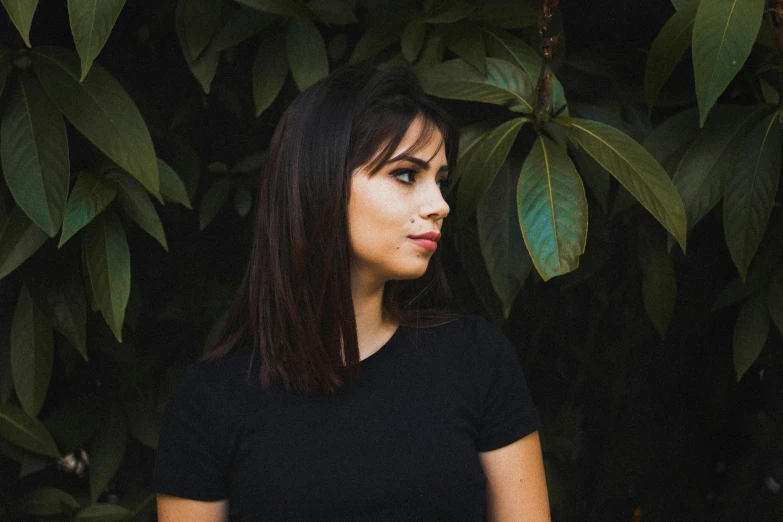 a young woman in front of green leaves in an urban area