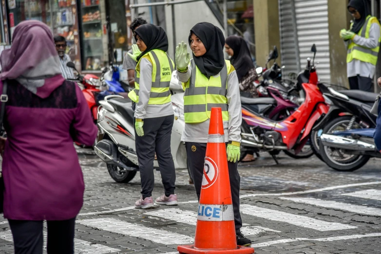 women in reflective vests standing near traffic cones on the side of the road