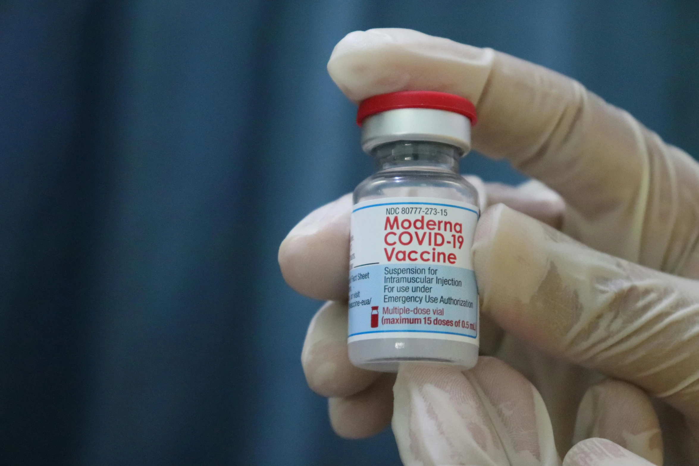 a hand in white glove holds up a medicine bottle