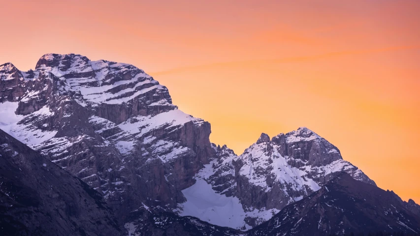 a picture taken from a plane of some snow - capped mountains at sunset