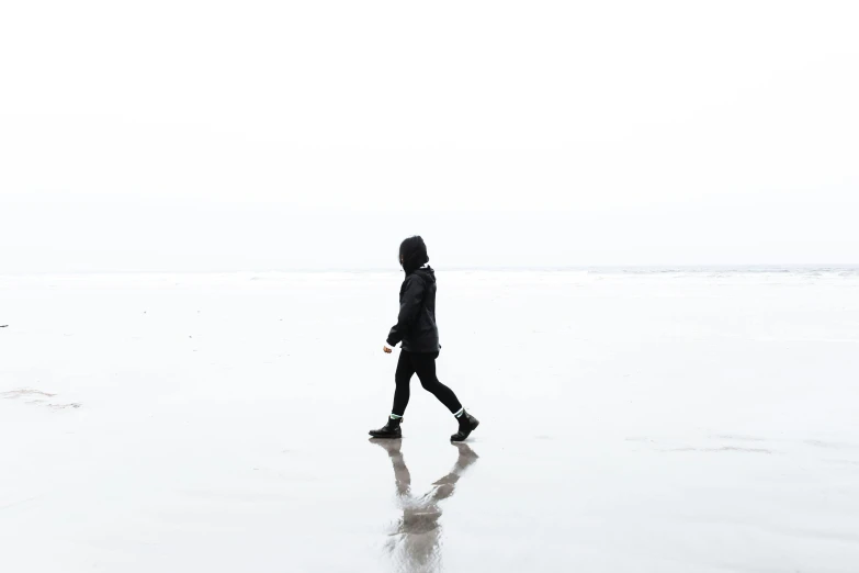 a person walks across the wet sand at the beach