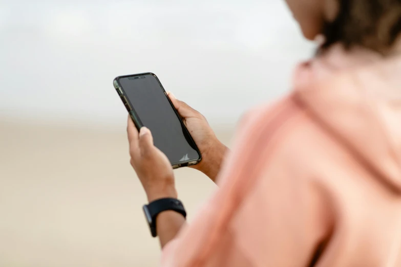 a woman looking at her cellphone while on the beach