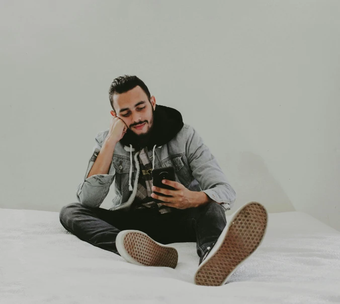 man in grey hoodie and black shoes with cell phone