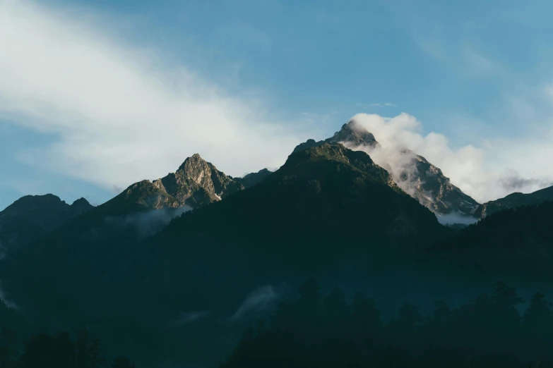 the silhouette of mountain peaks surrounded by clouds