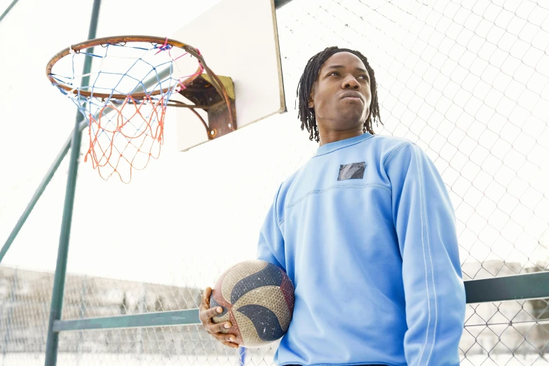 young man in blue sweater playing basketball on a sunny day