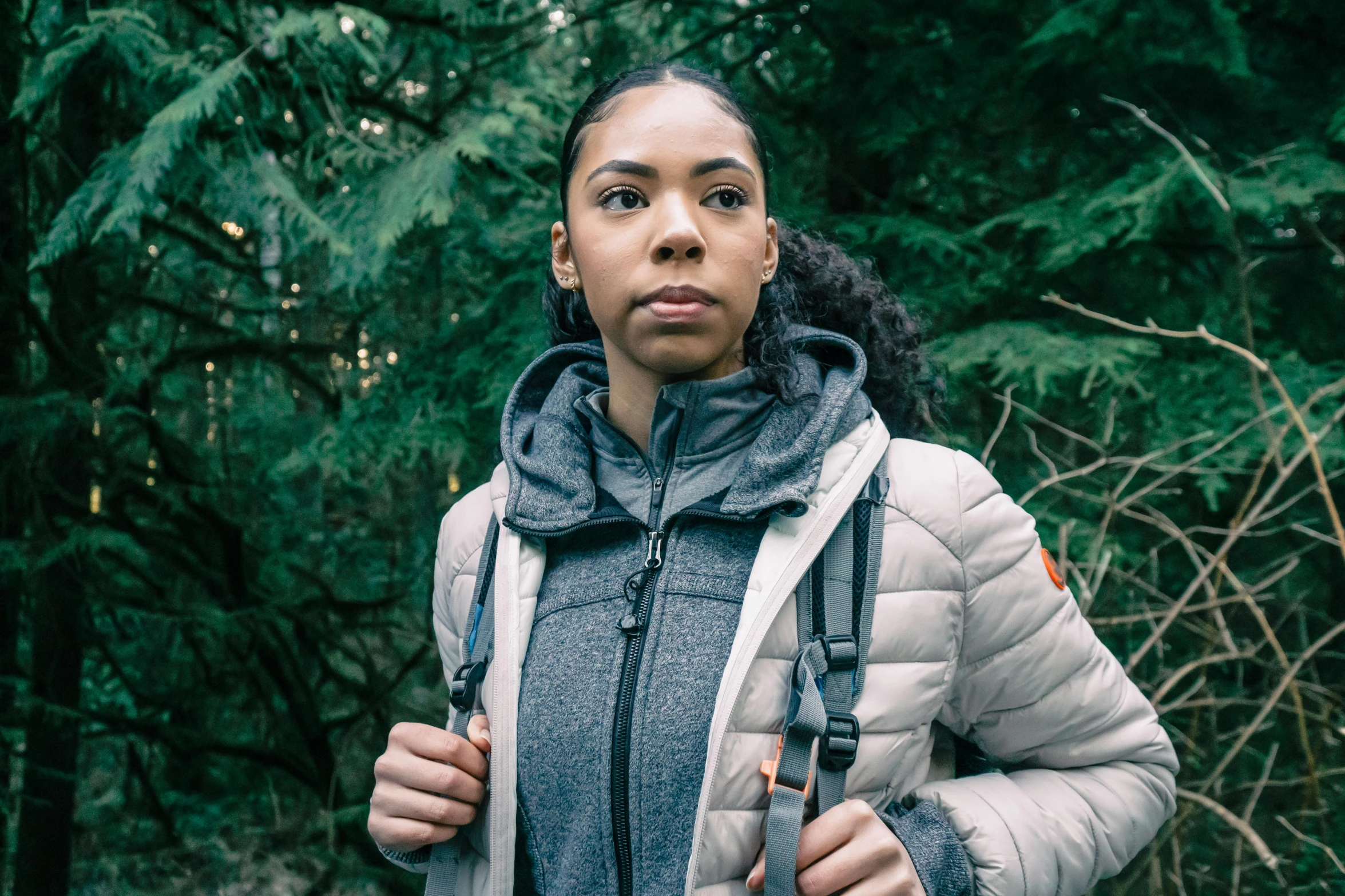 a young woman stands in the woods looking up