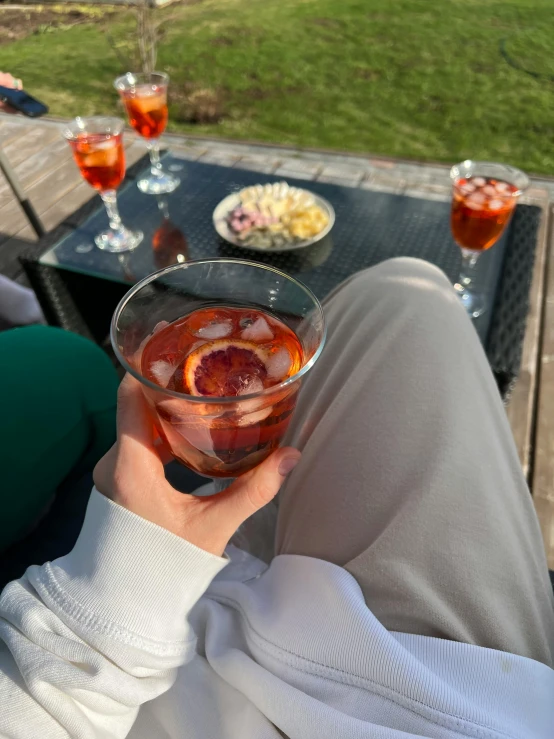 a person sitting outside holding up a drink