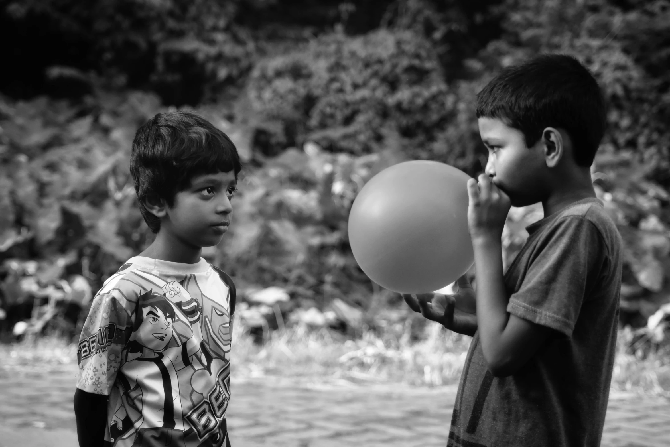 two children standing next to each other holding a ball