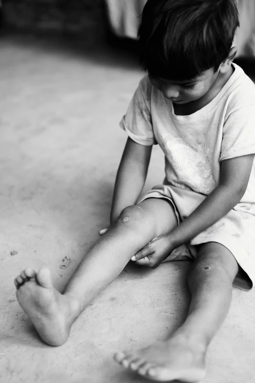 a child wearing pajamas sitting on the ground with their feet crossed