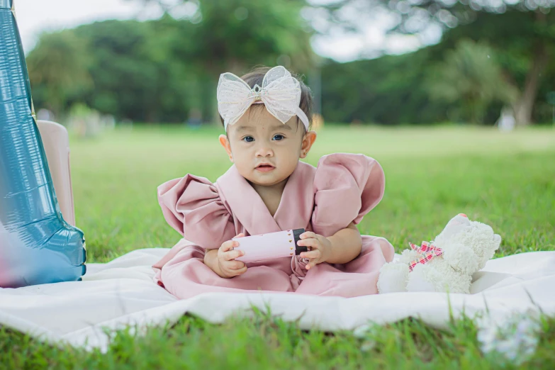 a baby is sitting on a blanket in the grass
