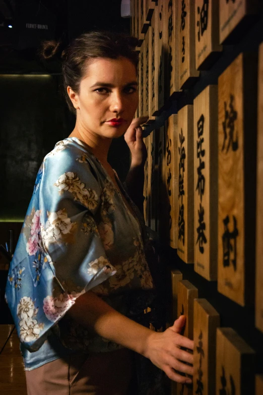 a woman is standing in a room with oriental writing on the wall