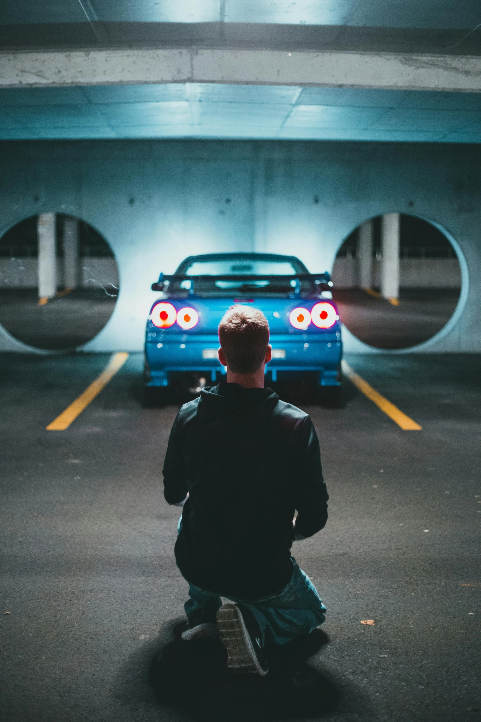 a person sits in front of a blue car