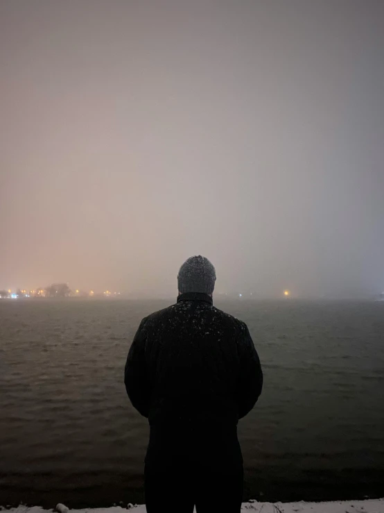 man watching the view from the shoreline on a foggy day