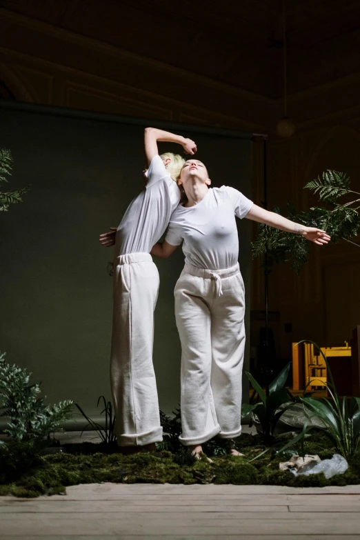 two women standing in front of some greenery