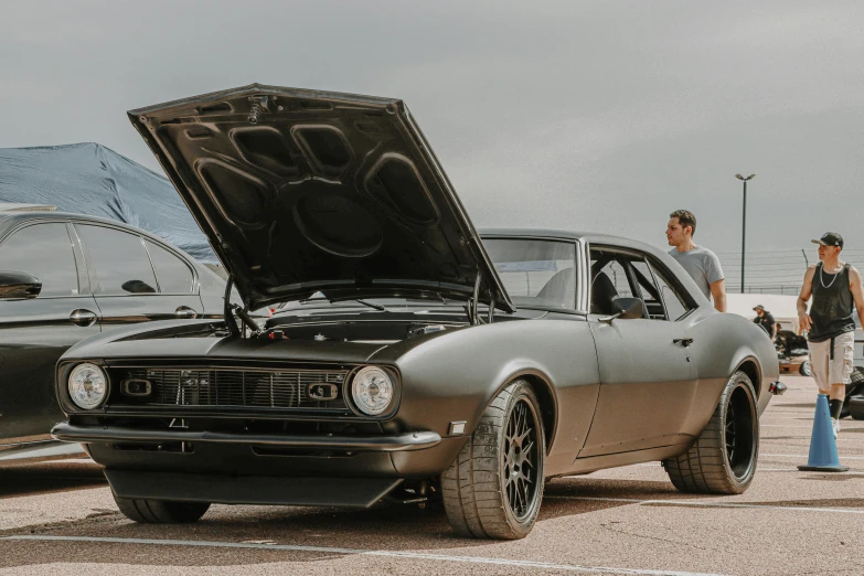 two men looking at a muscle car on display