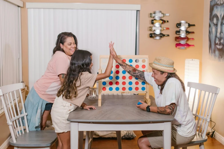 three children standing and playing around a wooden board game