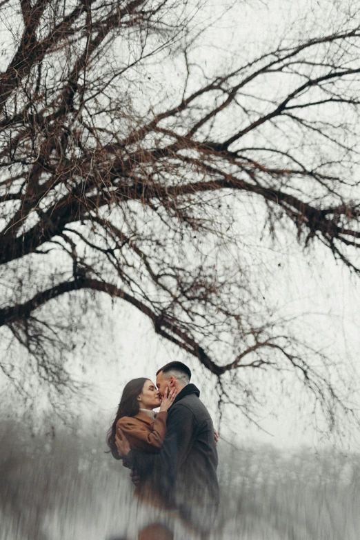 a couple kisses under a large tree