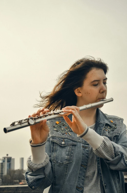 a woman holding a flute while leaning against a pole