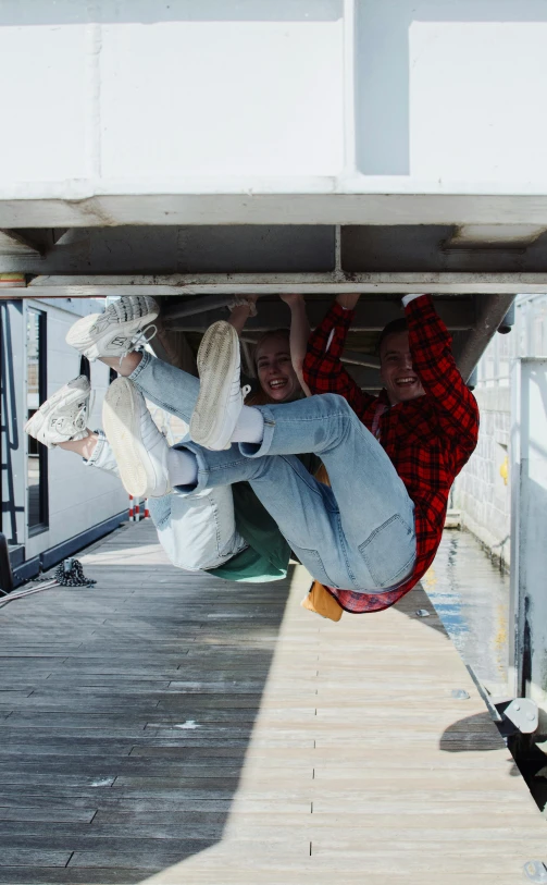 four children jumping on a wooden dock in the middle of a day