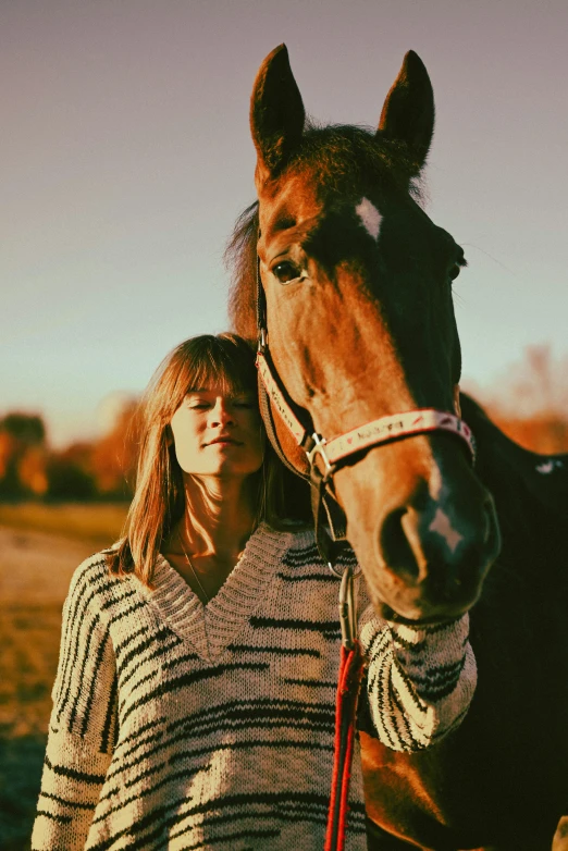 woman in striped top standing with horse near field