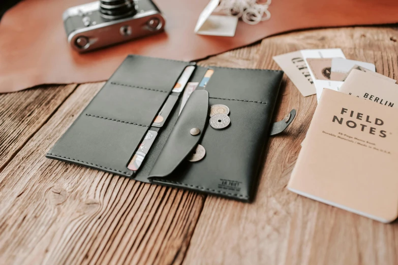 a leather cover, pen and money sit on a table