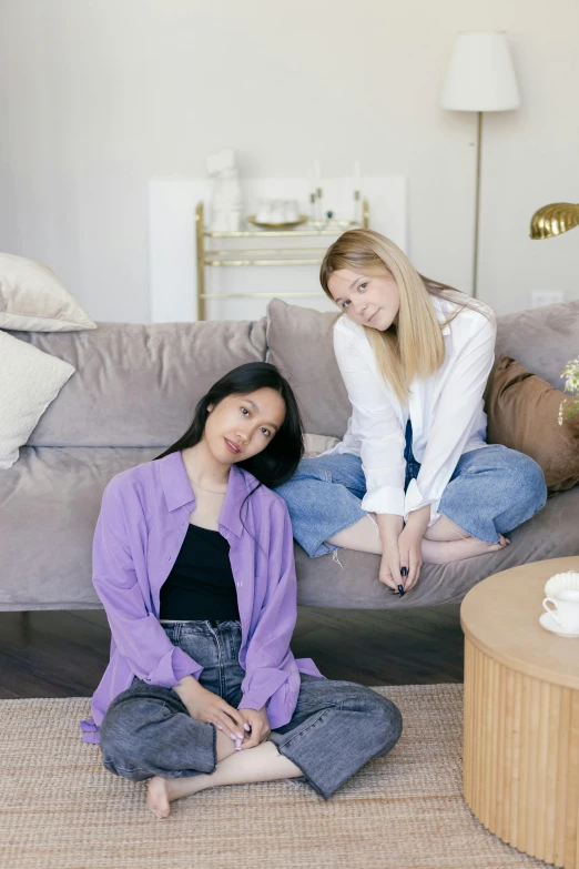 two girls pose on a couch next to each other