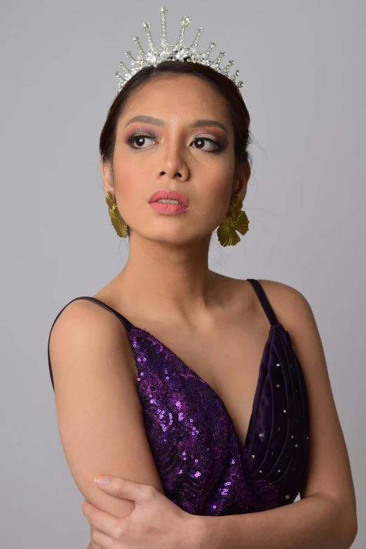 a woman in a purple dress with gold earrings