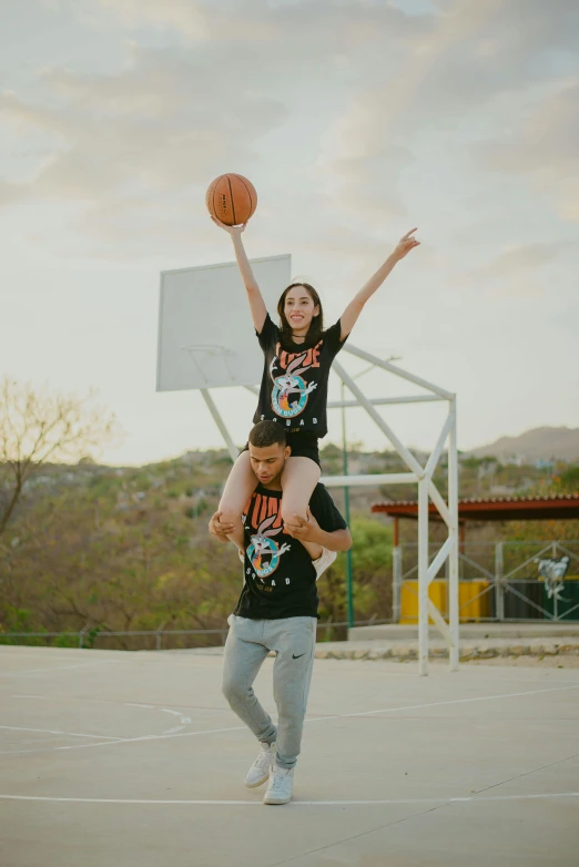 two girls are jumping and playing with a basketball in a court