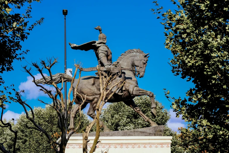 the statue of a man riding a horse is standing in front of a lamp post