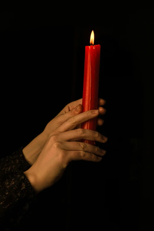 a candle burning red and lit in the dark