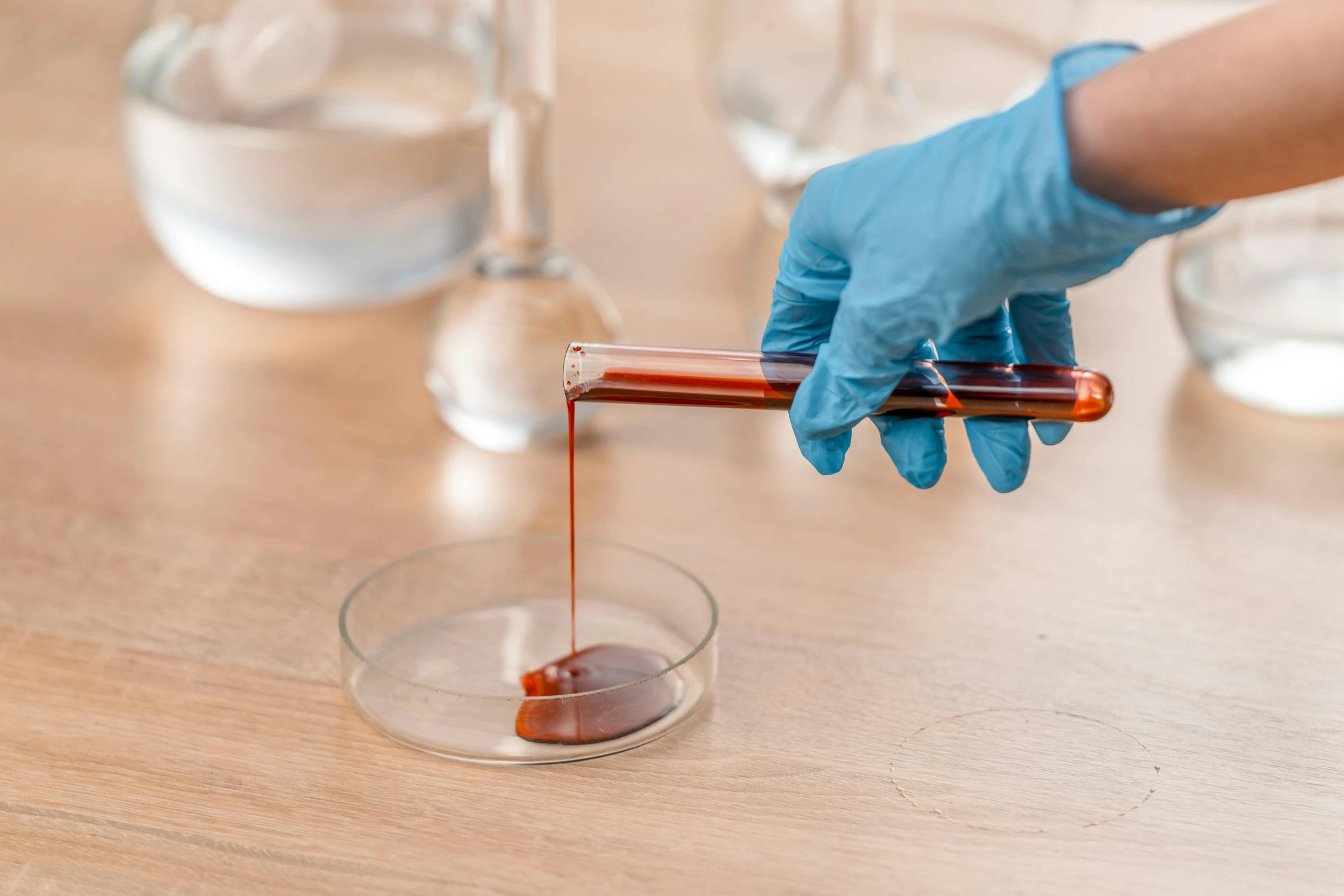 a person in gloves pours liquid from a test tube