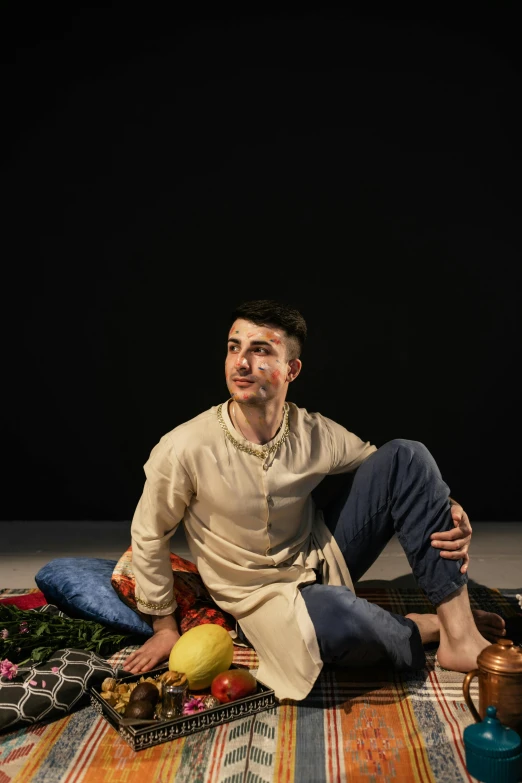 an individual posing for a pograph while sitting on a colorful mat