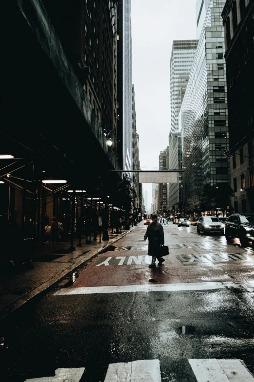 a person walking across the street on a rainy day