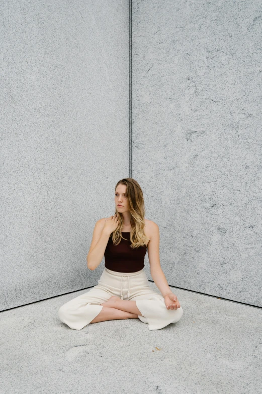 a woman sitting in a yoga position while holding her hands up