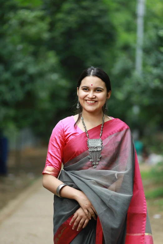 a smiling woman in a pink and gray sari