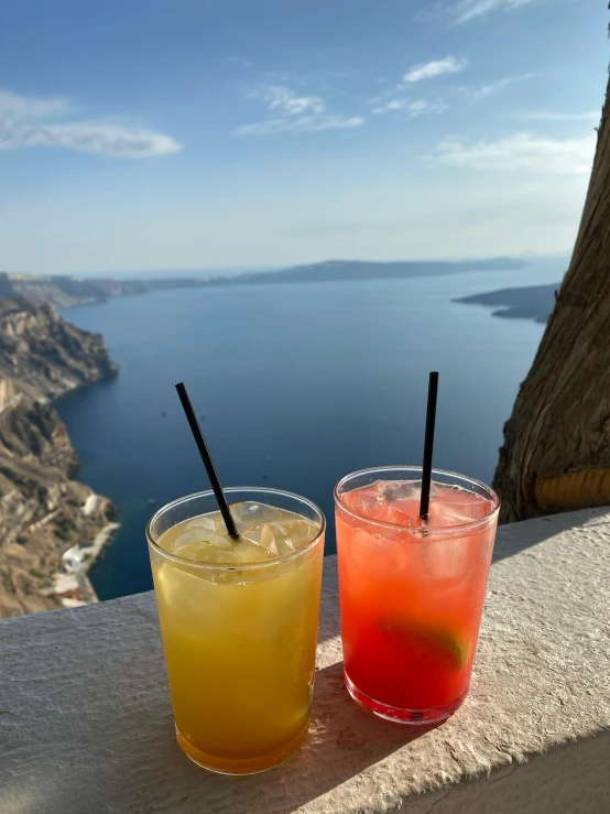 two glasses of drinks are lined up next to each other on a table