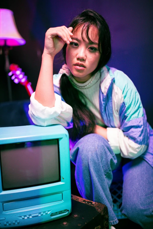 young woman sitting next to a small blue tv