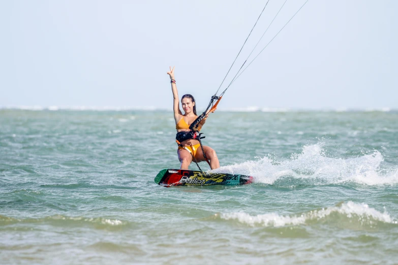 a girl windsurfing in the ocean with her hand up