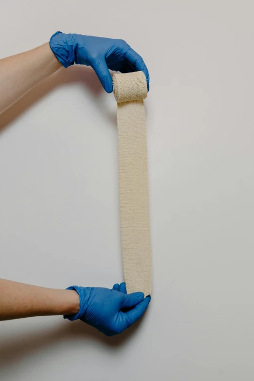 two hands are shown pulling the strap of bandage from the side