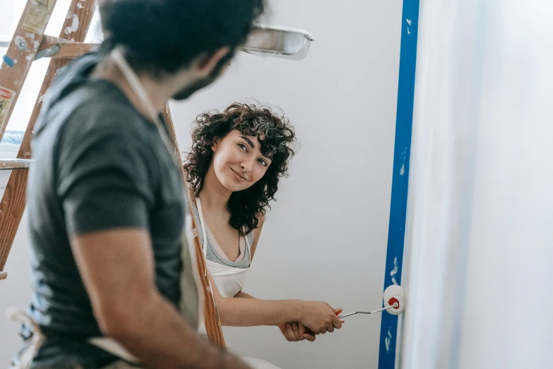 a woman holding a paintbrush brushes her teeth in the mirror